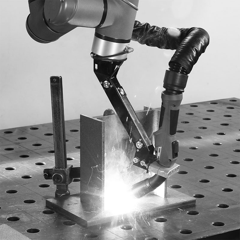 Der Kopf eines Schweißroboters, welche gerade Bauteile auf einer Werkbank schweißt.